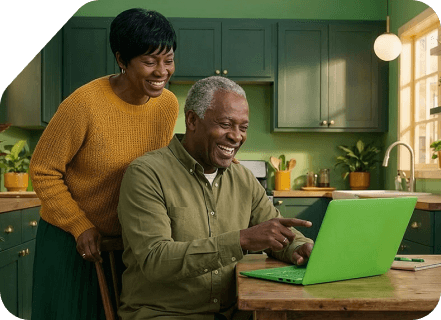 Smiling couple viewing laptop computer screen together in kitchen.